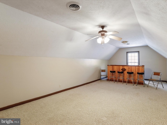 bonus room with vaulted ceiling, carpet flooring, ceiling fan, and a textured ceiling