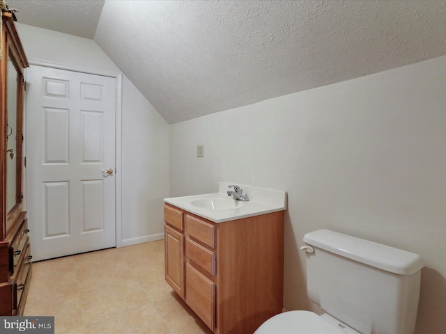 bathroom with toilet, vanity, vaulted ceiling, and a textured ceiling