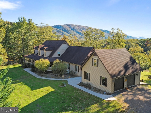 view of front of property featuring a front lawn, a garage, a mountain view, and a porch