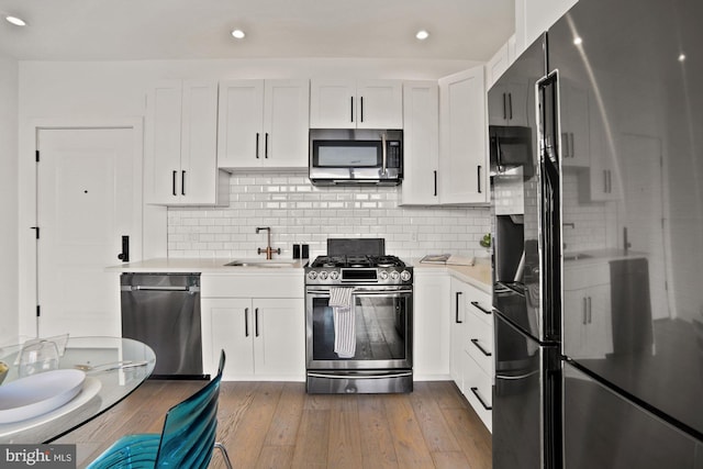 kitchen with hardwood / wood-style floors, white cabinets, stainless steel appliances, and backsplash