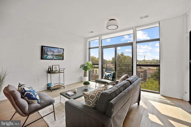 living room with expansive windows, light hardwood / wood-style flooring, and plenty of natural light