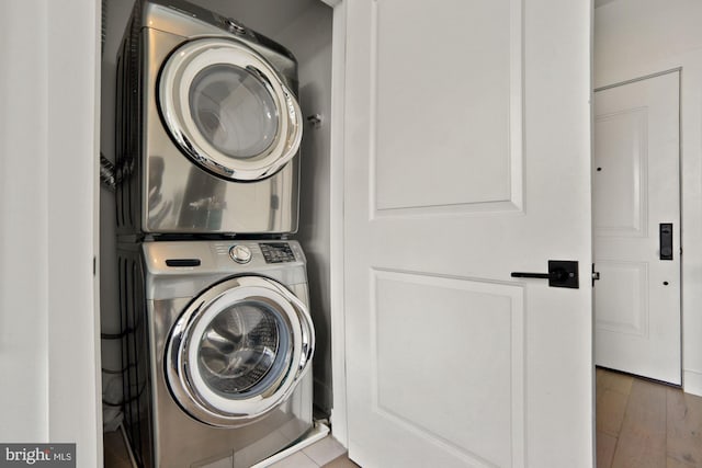 laundry area with stacked washing maching and dryer and hardwood / wood-style flooring