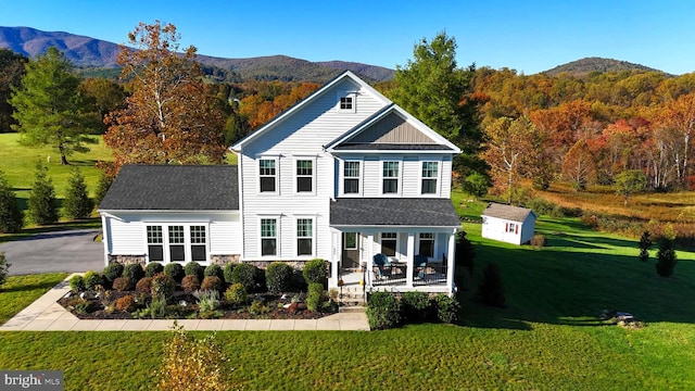 view of front of property featuring a mountain view, a front lawn, and a storage shed