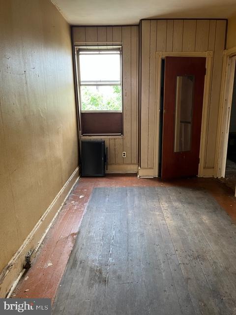 empty room featuring hardwood / wood-style floors and wooden walls