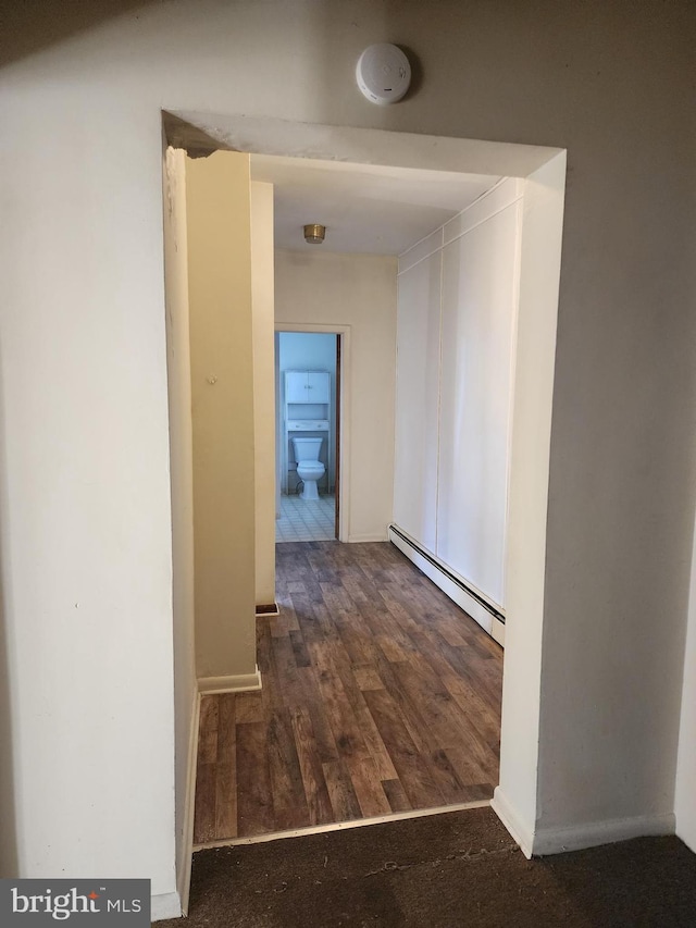 hall featuring a baseboard heating unit and dark hardwood / wood-style floors