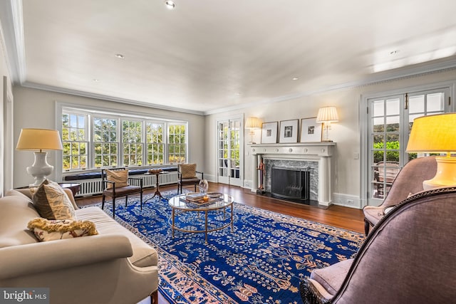 living room featuring a high end fireplace, hardwood / wood-style floors, and crown molding