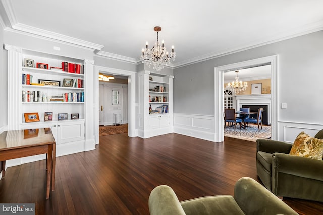 living room with dark hardwood / wood-style floors, radiator, crown molding, an inviting chandelier, and built in features