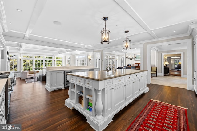 kitchen with white cabinetry, dark wood-type flooring, decorative light fixtures, a center island, and coffered ceiling