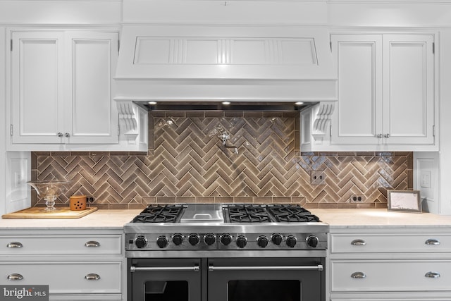 kitchen featuring decorative backsplash, white cabinetry, and stainless steel stove