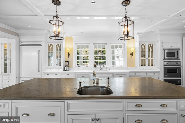 kitchen with sink, an island with sink, built in appliances, and decorative light fixtures