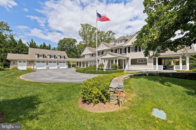 view of front facade featuring a porch, a front lawn, and a garage