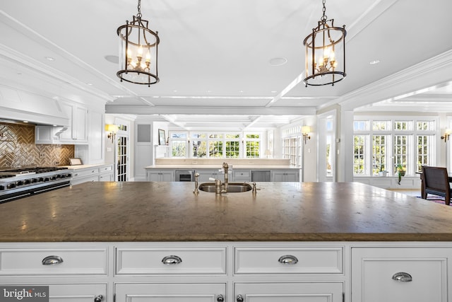 kitchen featuring sink, white cabinets, pendant lighting, and dark stone countertops