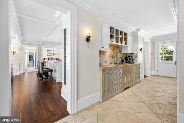 corridor with light hardwood / wood-style floors, crown molding, beamed ceiling, and sink