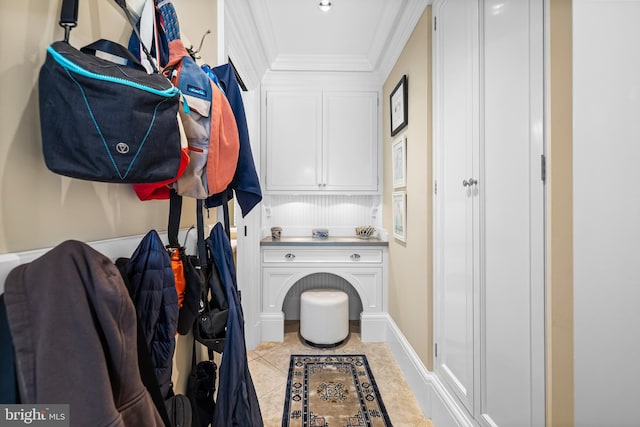 laundry area with ornamental molding and light tile patterned floors