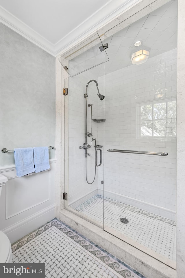 bathroom featuring a shower with door, crown molding, tile patterned floors, and toilet