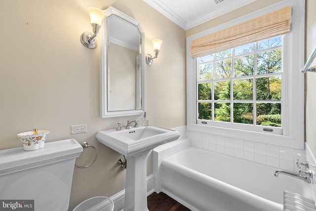 bathroom with toilet, a healthy amount of sunlight, crown molding, and a washtub