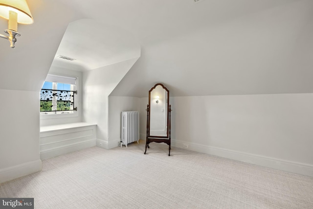 additional living space featuring lofted ceiling, light colored carpet, and radiator