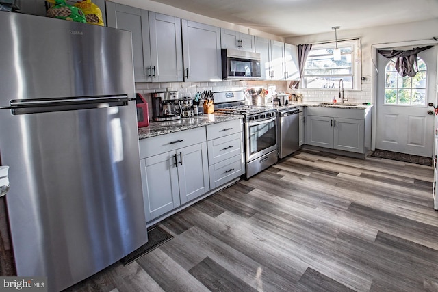 kitchen featuring stainless steel appliances, light stone countertops, sink, and tasteful backsplash