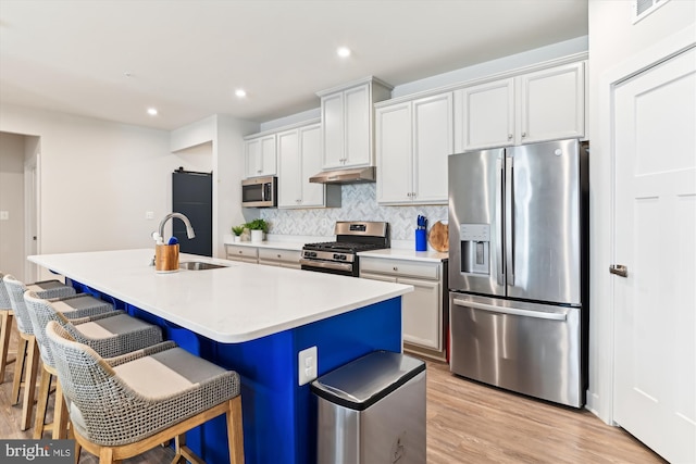 kitchen with light hardwood / wood-style flooring, appliances with stainless steel finishes, sink, and an island with sink