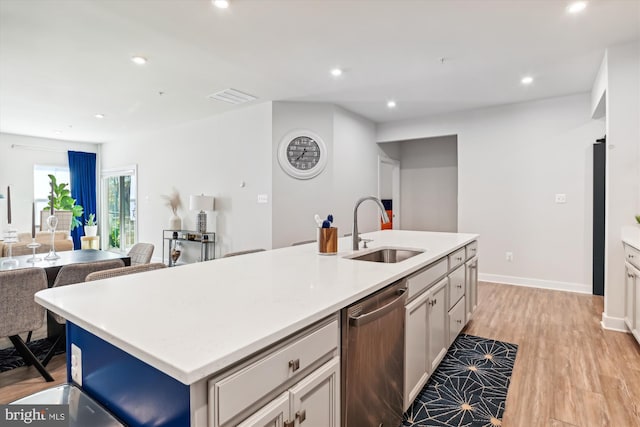 kitchen with a breakfast bar, a kitchen island with sink, light wood-type flooring, dishwasher, and sink