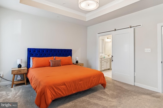 bedroom featuring ensuite bathroom, carpet, a tray ceiling, and a barn door