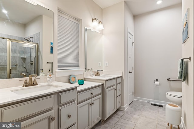 bathroom featuring toilet, tile patterned flooring, vanity, and a shower with door