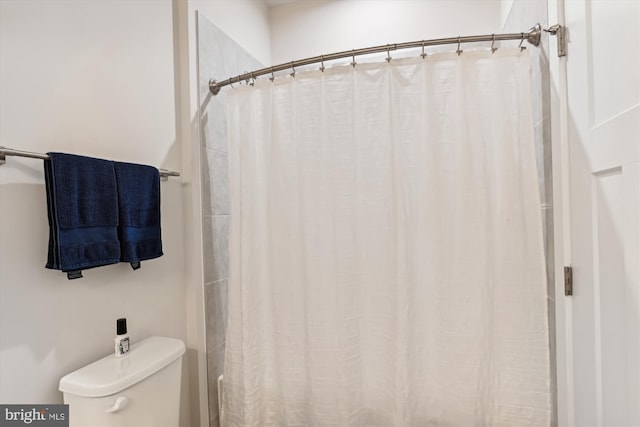 bathroom with toilet and a shower with shower curtain