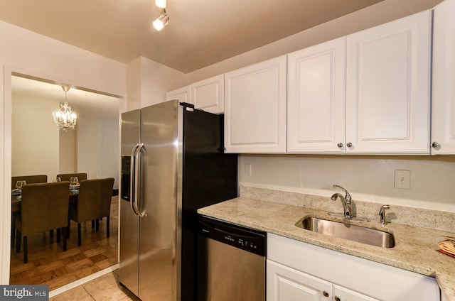 kitchen with white cabinetry, stainless steel appliances, sink, and decorative light fixtures