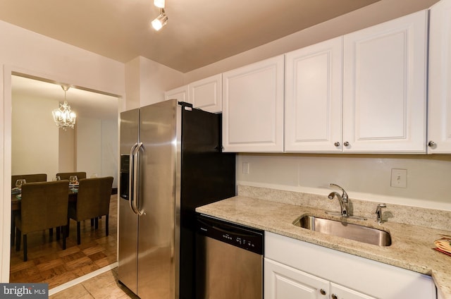 kitchen featuring a chandelier, white cabinets, stainless steel appliances, and a sink