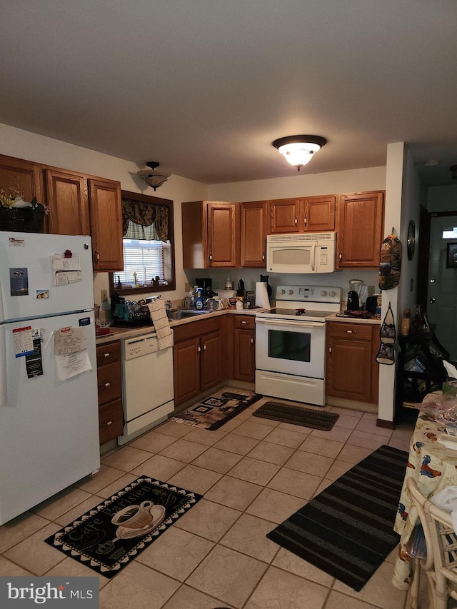 kitchen featuring white appliances, light tile patterned floors, and sink