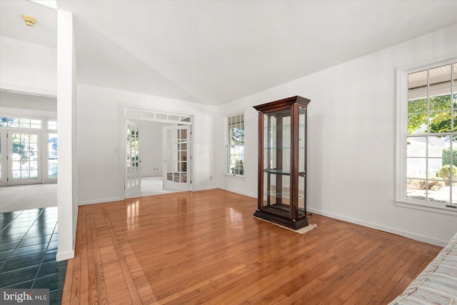 unfurnished living room featuring lofted ceiling, hardwood / wood-style floors, and a healthy amount of sunlight