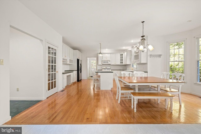 dining area featuring sink, light hardwood / wood-style flooring, and a notable chandelier