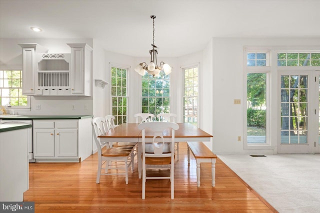 carpeted dining room featuring an inviting chandelier and a wealth of natural light