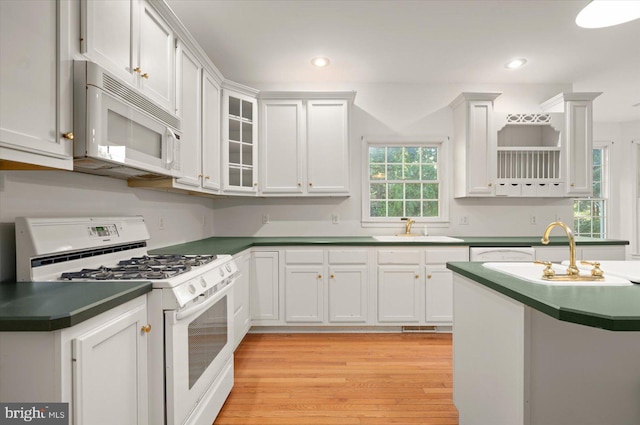 kitchen featuring light hardwood / wood-style floors, white cabinetry, sink, and white appliances