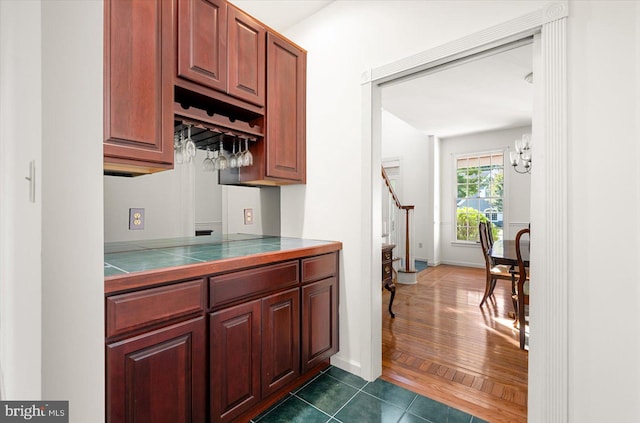 kitchen featuring tile countertops, an inviting chandelier, and dark hardwood / wood-style flooring