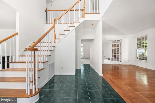 stairs featuring wood-type flooring and a towering ceiling