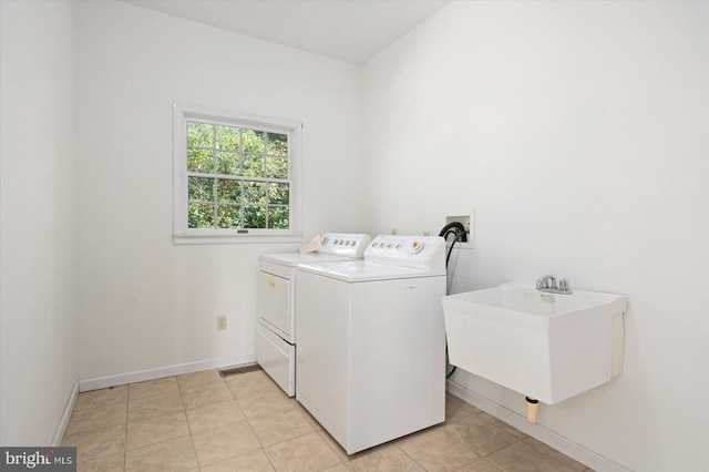 clothes washing area with sink, separate washer and dryer, and light tile patterned floors