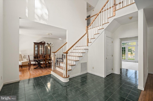 stairway featuring an inviting chandelier, wood-type flooring, and a high ceiling