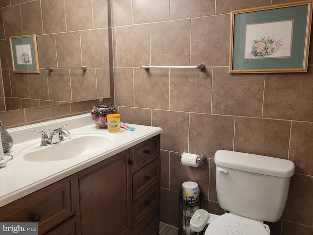 bathroom featuring tile walls, vanity, and toilet