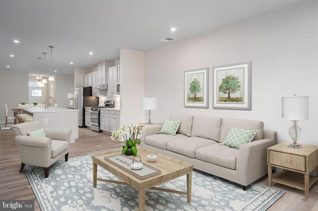 living room featuring an inviting chandelier, light hardwood / wood-style flooring, and sink