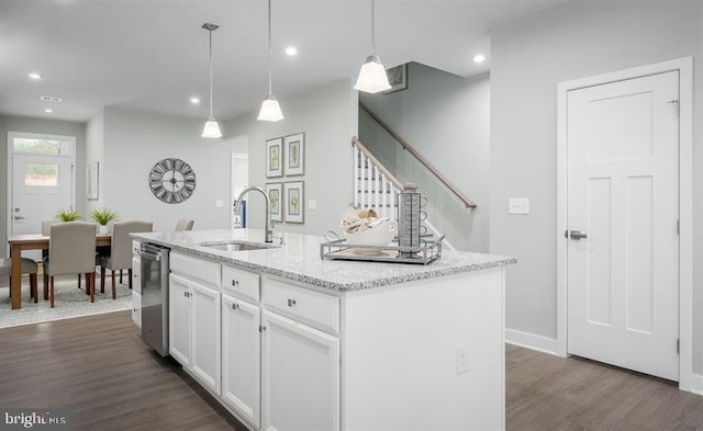 kitchen with hanging light fixtures, sink, an island with sink, and white cabinets