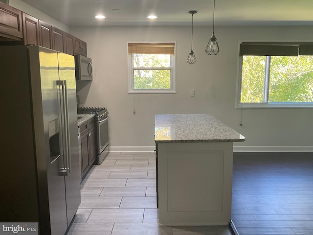 kitchen featuring light stone countertops, appliances with stainless steel finishes, and hanging light fixtures