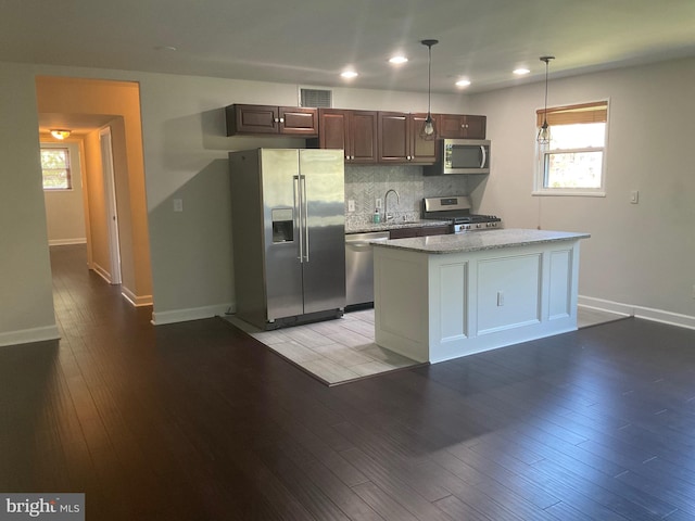 kitchen with dark brown cabinets, light wood-type flooring, stainless steel appliances, pendant lighting, and a center island