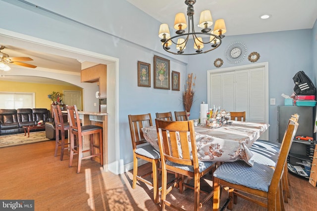 dining space with ceiling fan with notable chandelier and hardwood / wood-style floors