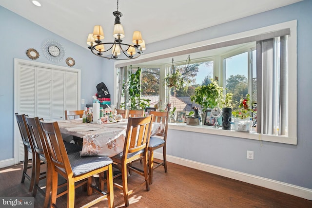 dining area with dark wood-type flooring, vaulted ceiling, and a chandelier