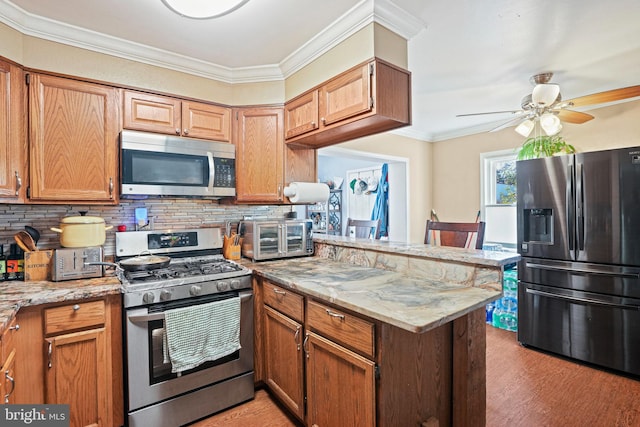 kitchen featuring crown molding, light stone countertops, stainless steel appliances, and kitchen peninsula