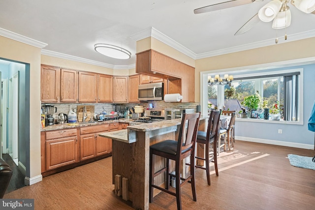 kitchen featuring ornamental molding, decorative backsplash, stainless steel appliances, and light hardwood / wood-style floors