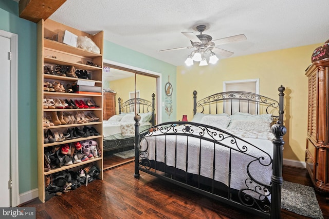 bedroom with ceiling fan, a textured ceiling, and dark hardwood / wood-style flooring