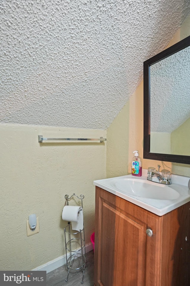 bathroom with vanity, a textured ceiling, and lofted ceiling