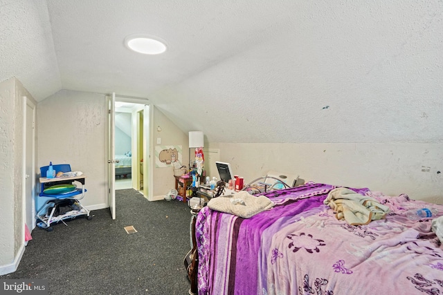 bedroom with lofted ceiling, a textured ceiling, and dark carpet